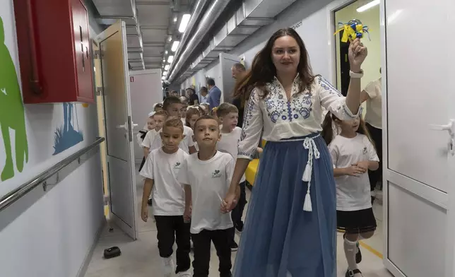 A teacher rings the bell on the first day in an underground school in Kharkiv, Ukraine, Monday, Sept. 1, 2025. (AP Photo/Andrii Marienko)