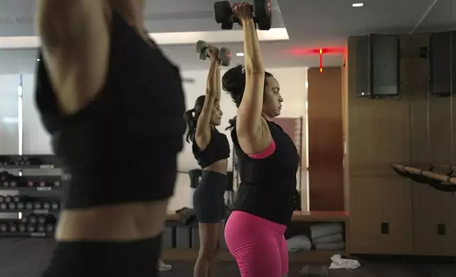 CORRECTS YEAR TO 2025, NOT 2024 - Jannelliz Barragan, center, wears a weighted vest during an MB360 workout class at the Life Time health club in New York on Wednesday, Aug. 13, 2025. (AP Photo/Shelby Lum)