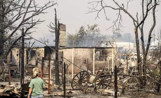 A resident passes a home destroyed by the TCU September Lightning Complex fire in the Chinese Camp community of Tuolumne County, Calif., on Wednesday, Sept. 3, 2025. (AP Photo/Noah Berger)