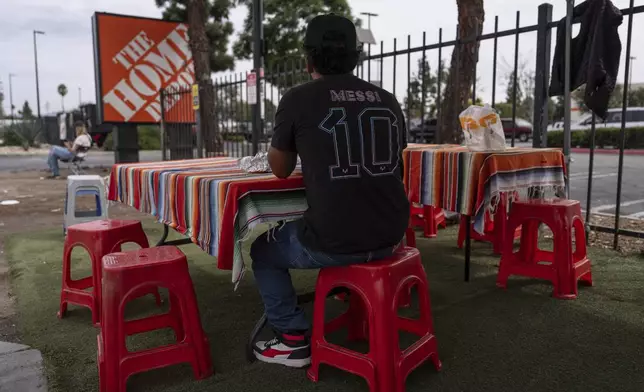 A day laborer eats his meal near a Home Depot sign in the Van Nuys section of Los Angeles, Thursday, Aug. 28, 2025. (AP Photo/Jae C. Hong)
