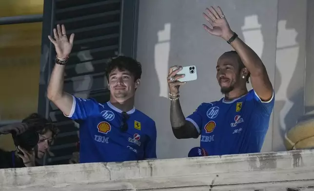 Ferrari driver Lewis Hamilton of Britain, right, and his teammate Charles Leclerc of Monaco, wave to fans from a balcony on the occasion of a sponsor event in Milan, Italy, Wednesday, Sept. 3, 2025. The Formula one race will be held on Sunday. (AP Photo/Luca Bruno)