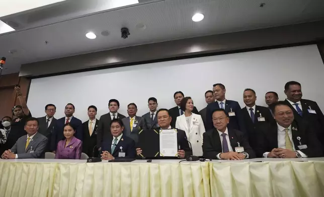 Leader of Bhumjai Thai Party Anutin Charnvirakul, fourth left in front, shows the signed Memorandum of Understanding between his coalition parties and the People's party at Parliament in Bangkok, Thailand, Wednesday, Sept. 3, 2025. (AP Photo/Sakchai Lalit)