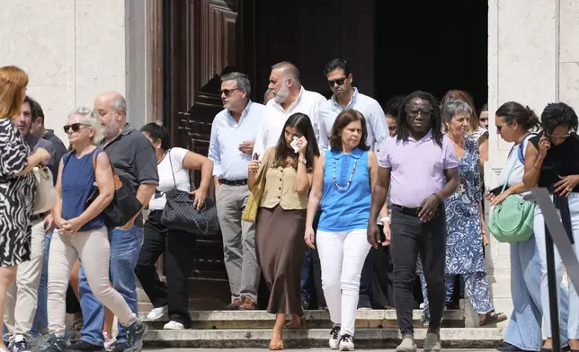 Relatives, friends and colleagues leave a church service for the four coworkers of the charitable organization Santa Casa da Misericordia who perished in the derailment and crash of the Gloria funicular, at the Church of Saint Roch in Lisbon, Friday, Sept. 5, 2025. (AP Photo/Armando Franca)