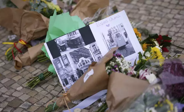 Images of streetcars with messages placed next to flowers, are photographed at the site where a tourist streetcar derailed and crashed in Lisbon, Portugal, Friday, Sept. 5, 2025. (AP Photo/Armando Franca)