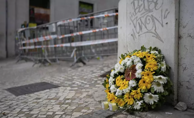 Flowers are photographed at the site where a tourist streetcar derailed and crashed in Lisbon, Portugal, Friday, Sept. 5, 2025. (AP Photo/Armando Franca)