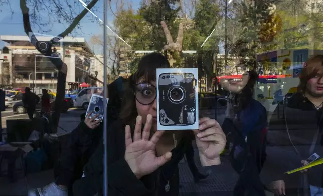 A student looks through the lens hole of a paper camera while visiting an exhibit at the Gabriela Mistral gallery in Santiago, Chile, Thursday, Sept. 4, 2025. (AP Photo/Esteban Felix)