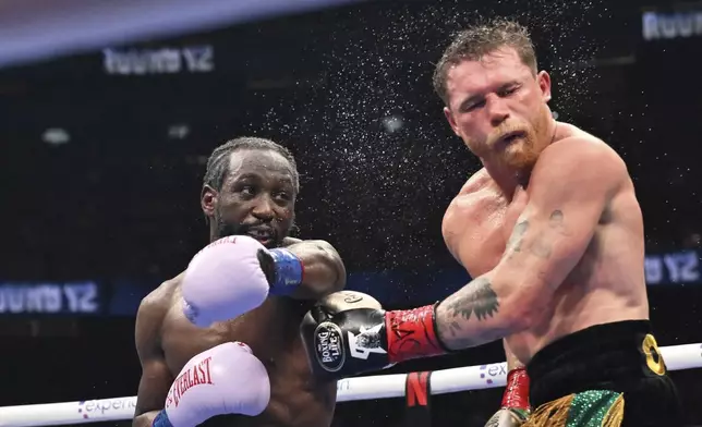 Terence Crawford, left, punches Canelo Alvarez during an undisputed super middleweight championship boxing match in Las Vegas, Saturday, Sept. 13, 2025. (AP Photo/David Becker)