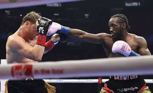 Terence Crawford, right, throws a punch at Canelo Alvarez during an undisputed super middleweight championship boxing match in Las Vegas, Saturday, Sept. 13, 2025. (AP Photo/David Becker)