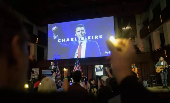 People hold candles and sing during a memorial and prayer vigil for Charlie Kirk at the John F. Kennedy Memorial Center for the Performing Arts, Sunday, Sept. 14, 2025, in Washington. (AP Photo/Rod Lamkey, Jr.)