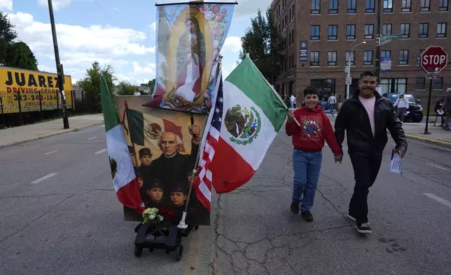People walks along the route during the 2025 Pilsen Mexican Independence Day parade Saturday, Sept. 6, 2025, in Chicago. (AP Photo/Carolyn Kaster)