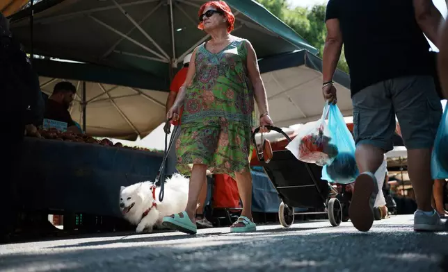 People shop at an open-air fruit and vegetable market in Athens, Greece, Friday, Sept. 5, 2025. (AP Photo/Thanassis Stavrakis)