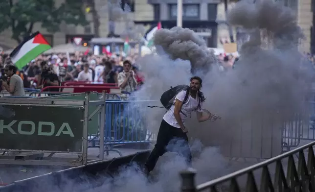 Protesters clash with police as they block the road trying to disrupt the twenty-first stage of the Spanish cycling race La Vuelta, from Alalpardo to Madrid, Spain, Sunday, Sept. 14, 2025. (AP Photo/Manu Fernández)