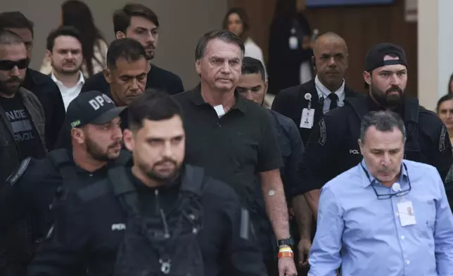 Former President Jair Bolsonaro, center, temporarily allowed out of house arrest for medical treatment, departs a hospital in Brasilia, Brazil, Sunday, Sep. 14, 2025. (AP Photo/Luis Nova)