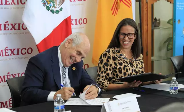 Santa Fe Mayor Alan Webber and Patricia Pinzon, Consul of Mexico in Albuquerque, sign documents returning a centuries-old map to Mexico's national archives during a ceremony in Albuquerque, New Mexico, on Tuesday, Sept. 23, 2025. (AP Photo/Susan Montoya Bryan)