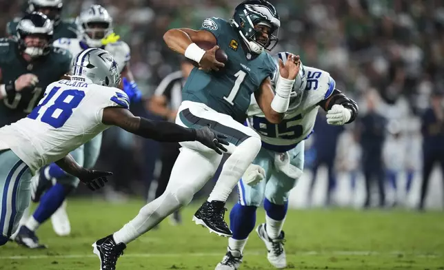 Philadelphia Eagles quarterback Jalen Hurts (1) runs the ball as Dallas Cowboys' Damone Clark (18) and Kenny Clark (95) attempt to make the stop in the first half of an NFL football game Thursday, Sept. 4, 2025, in Philadelphia. (AP Photo/Matt Slocum)