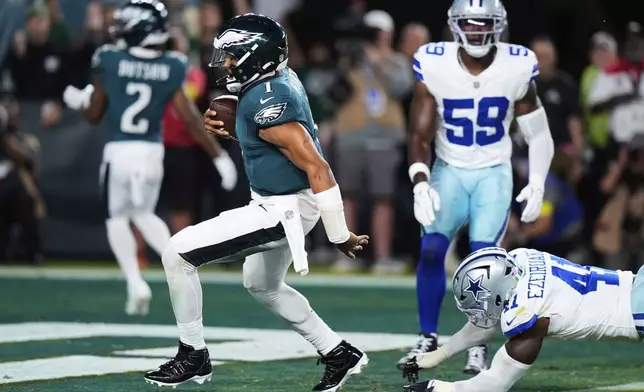 Philadelphia Eagles quarterback Jalen Hurts (1) runs the ball for a touchdown as after getting past Dallas Cowboys defensive end Donovan Ezeiruaku (41) in the first half of an NFL football game Thursday, Sept. 4, 2025, in Philadelphia. (AP Photo/Chris Szagola)