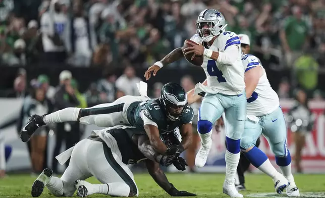Dallas Cowboys quarterback Dak Prescott (4) escapes pressure from Philadelphia Eagles linebacker Patrick Johnson (48) and others in the first half of an NFL football game Thursday, Sept. 4, 2025, in Philadelphia. (AP Photo/Matt Slocum)