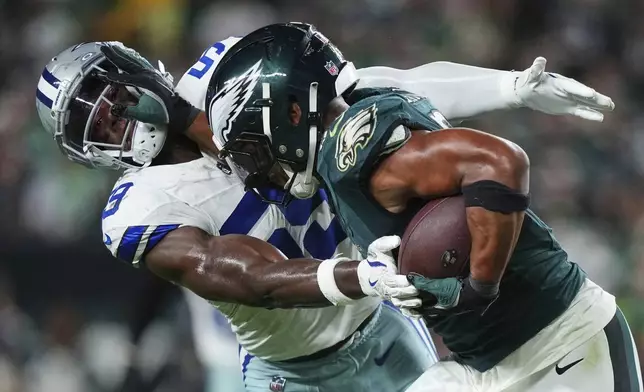 Philadelphia Eagles running back Saquon Barkley, right, fights off a tackle attempt by Dallas Cowboys linebacker Kenneth Murray Jr. (59) in the second half of an NFL football game Thursday, Sept. 4, 2025, in Philadelphia. (AP Photo/Matt Slocum)