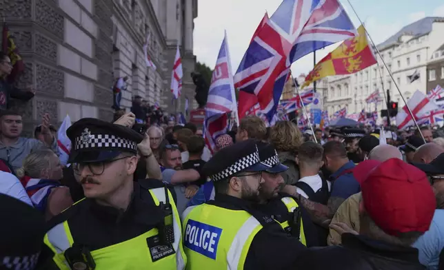Police officers form a line in front of demonstrators from the Tommy Robinson-led Unite the Kingdom march and rally near Westminster, London, Saturday Sept. 13, 2025. (AP Photo/Joanna Chan)