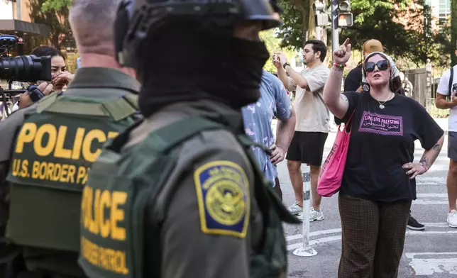 Pedestrians yell at federal agents from U.S. Immigration and Customs Enforcement and U.S. Customs and Border Protection as they stand on North Clark Street at West Oak Street in River North, Sunday, Sept. 28, 2025, in Chicago. (Ashlee Rezin/Chicago Sun-Times via AP)