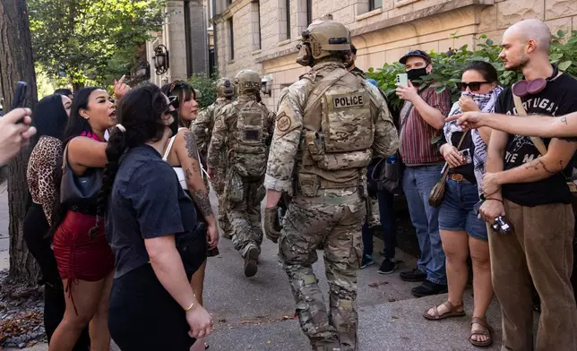 Pedestrians yell at federal agents from U.S. Immigration and Customs Enforcement and U.S. Customs and Border Protection as they walk along North Clark Street near West Oak Street in the River North neighborhood, Sunday, Sept. 28, 2025, in Chicago. (Ashlee Rezin/Chicago Sun-Times via AP)