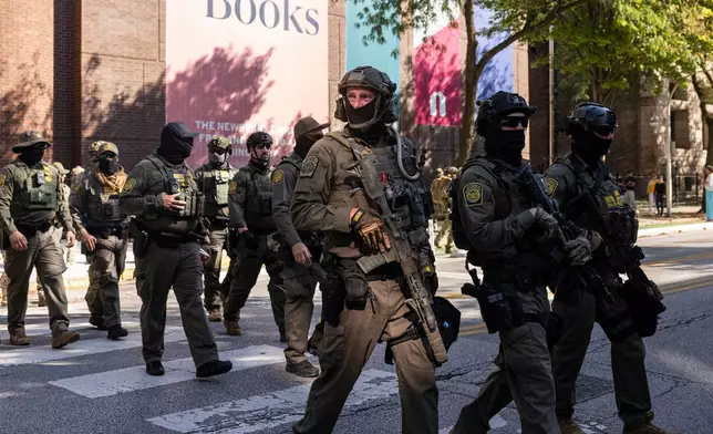 Federal agents from U.S. Immigration and Customs Enforcement and U.S. Customs and Border Protection cross North Clark Street at West Oak Street in River North, Sunday, Sept. 28, 2025, in Chicago. (Ashlee Rezin/Chicago Sun-Times via AP)