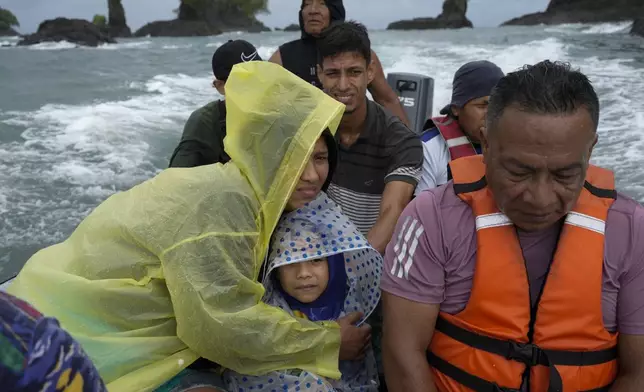 Venezuelan Mariela Gomez holds her son Mathias as they boat to shore after arriving on a larger cargo vessel in Jaque, on Panama's Pacific coast, Thursday, Sept. 18, 2025, during their journey south after giving up on reaching the United States. (AP Photo/Matias Delacroix)