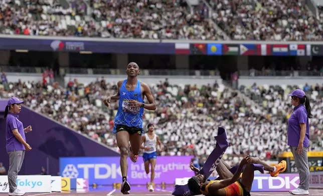 Tanzania's Alphonce Felix Simbu, left, wins the gold in the men's marathon ahead of Germany's Amanal Petros who falls at the World Athletics Championships in Tokyo, Monday, Sept. 15, 2025. (AP Photo/Petr David Josek)