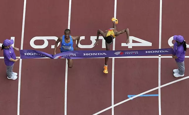 Tanzania's Alphonce Felix Simbu, left, crosses the finish line ahead of Germany's Amanal Petros to win the men's marathon at the World Athletics Championships in Tokyo, Monday, Sept. 15, 2025. (AP Photo/Bernat Armangue)