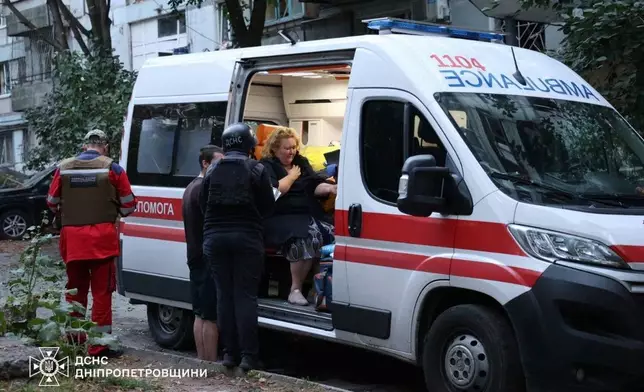 In this photo provided by the Ukrainian Emergency Services on Saturday, Sept. 20, 2025, an injured woman sits in ambulance near a residential house damaged by a Russian strike on Dnipro, Ukraine. (Ukrainian Emergency Service via AP)