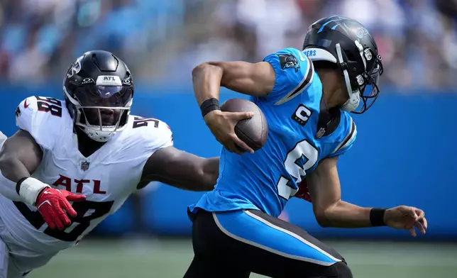 Carolina Panthers quarterback Bryce Young runs past Atlanta Falcons defensive tackle Ruke Orhorhoro during the first half of an NFL football game, Sunday, Sept. 21, 2025, in Charlotte, N.C. (AP Photo/Jacob Kupferman)