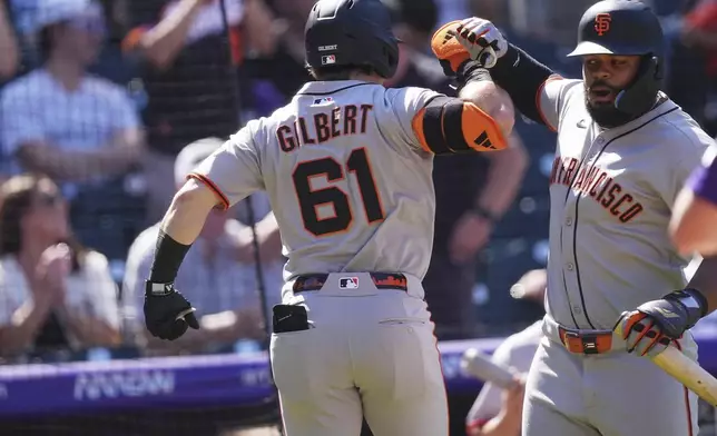 San Francisco Giants' Heliot Ramos, right, congratulates Drew Gilbert(61) who returns to the dugout after hitting a two-run home run off Colorado Rockies starting pitcher Chase Dollander in the third inning of a baseball game Monday, Sept. 1, 2025, in Denver. (AP Photo/David Zalubowski)