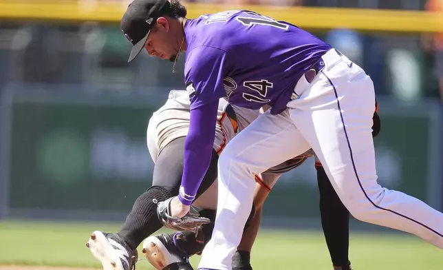 Colorado Rockies shortstop Ezequiel Tovar, front, tags out San Francisco Giants' Heliot Ramos, back, at second base as Ramos tried to stretch a single into a double in the third inning of a baseball game Monday, Sept. 1, 2025, in Denver. (AP Photo/David Zalubowski)