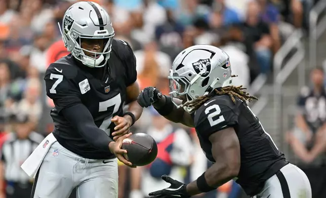 Las Vegas Raiders quarterback Geno Smith (7) hands the ball to running back Ashton Jeanty (2) during the first half of an NFL football game against the Chicago Bears Sunday, Sept. 28, 2025, in Las Vegas. (AP Photo/David Becker)