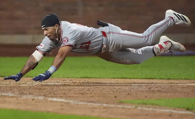 Washington Nationals' Daylen Lile dives to home plate to score on a two-run inside-the-park home run during the 11th inning of a baseball game against the New York Mets Saturday, Sept. 20, 2025, in New York. (AP Photo/Frank Franklin II)
