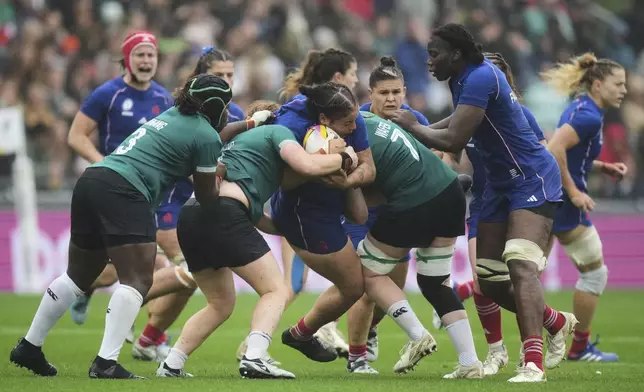 France's Assia Khalfaoui, center, is tackled by Ireland's Aoife Wafer, right, and her teammates during a Women's Rugby World Cup 2025 quarterfinal match between France and Ireland, in Exeter, England, Sunday, Sept. 14, 2025. (AP Photo/Alastair Grant)