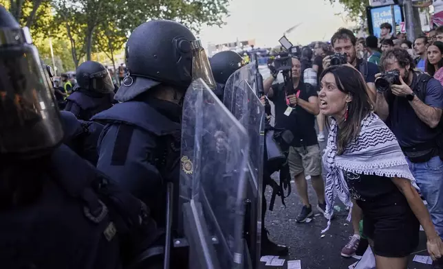 A protester argues with police as they try to disrupt the twenty-first stage of the Spanish cycling race La Vuelta, from Alalpardo to Madrid, Spain, Sunday, Sept. 14, 2025. (AP Photo/Andrea Comas)