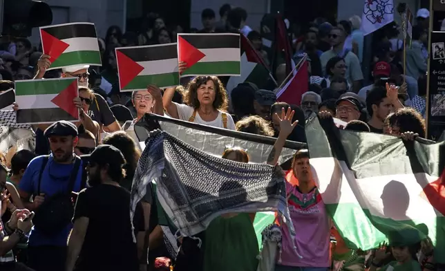 People shout slogans and hold Palestinian flags while protesting during the twenty-first stage of La Vuelta cycling race from Alalpardo to Madrid, Spain, Sunday, Sept. 14, 2025. (AP Photo/Andrea Comas)
