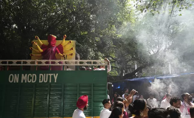Devotees sing and dance as they transport an idol of the Hindu goddess Durga to their place of worship ahead of the Durga Puja festival in New Delhi, India, Sunday, Sept. 21, 2025. (AP Photo/Manish Swarup)