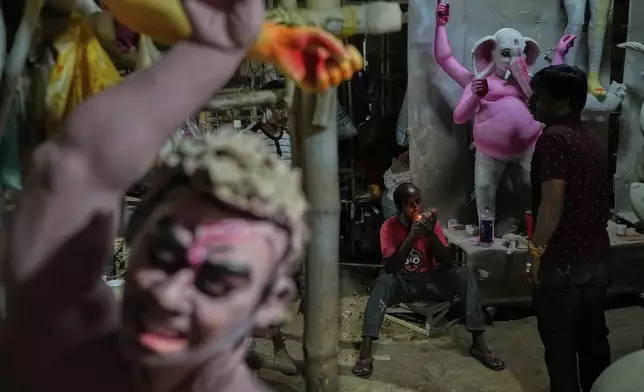 Workers take a break while creating idols of Hindu deities ahead of the Durga Puja festival in New Delhi, India, Friday, Sept. 19, 2025. (AP Photo/Manish Swarup)