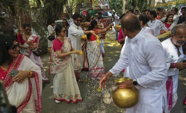 Devotees sprinkle water and throw flower petals on the road through which they will be taking out the Hindu goddess Durga idol on a truck to a place of worship ahead of the Durga Puja festival in New Delhi, India, Sunday, Sept. 21, 2025.. (AP Photo/Manish Swarup)