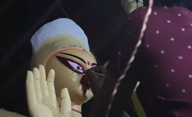 Govind Nath from Kolkata paints the eye of an idol of the Hindu goddess Durga ahead of the Durga Puja festival in New Delhi, India, Friday, Sept. 19, 2025. (AP Photo/Manish Swarup)