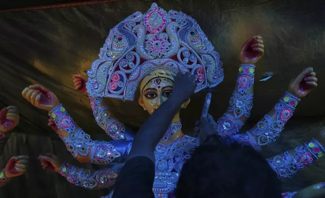 An artist attaches a crown to an idol of the Hindu goddess Durga ahead of the Durga Puja festival in New Delhi, India, Saturday, Sept. 20, 2025 (AP Photo/Manish Swarup)