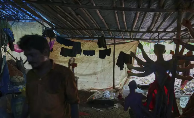 An artist walks past his living quarters in a temporary shelter where he and others are creating idols of Hindu gods and goddesses ahead of the Durga Puja festival in New Delhi, India, Saturday, Sept. 20, 2025 (AP Photo/Manish Swarup)