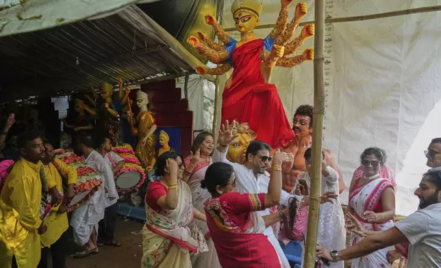 Devotees sing and dance as they gather at a temporary shelter to take an idol of the Hindu goddess Durga to their place of worship ahead of the Durga Puja festival in New Delhi, India, Sunday, Sept. 21, 2025. (AP Photo/Manish Swarup)