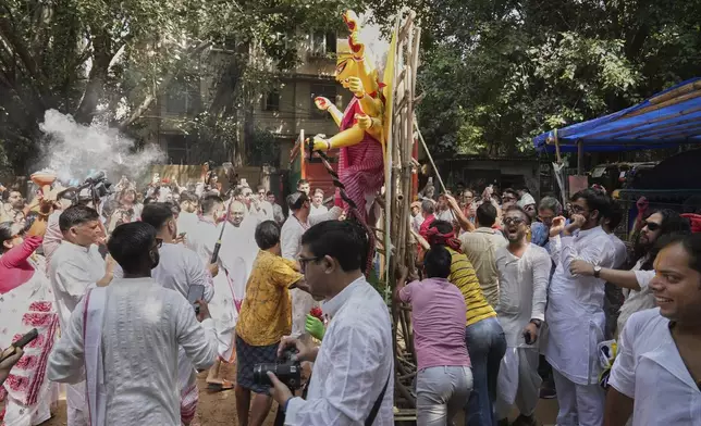 Devotees sing and dance as they prepare to take an idol of the Hindu goddess Durga to their place of worship ahead of the Durga Puja festival in New Delhi, India, Sunday, Sept. 21, 2025. (AP Photo/Manish Swarup)