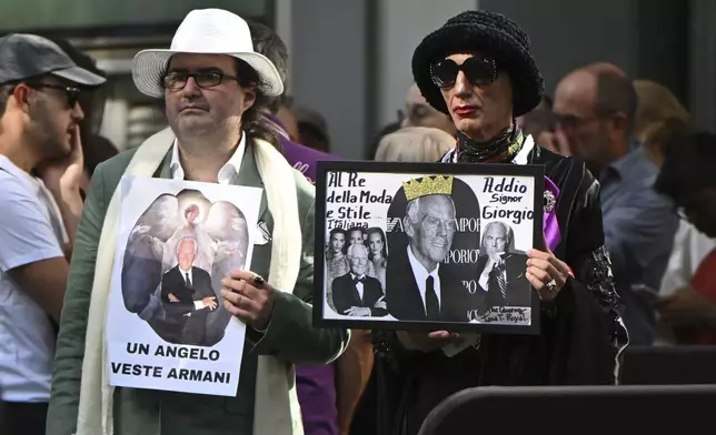 Fans display placards in Italian reading: "An angel wears Armani" outside the Armani/Teatro in Milan, northern Italy, to pay their respects to designer Giorgio Armani, who died Thursday at age 91, Sunday, Sept. 7, 2025. (AP Photo/Nicola Marfisi)