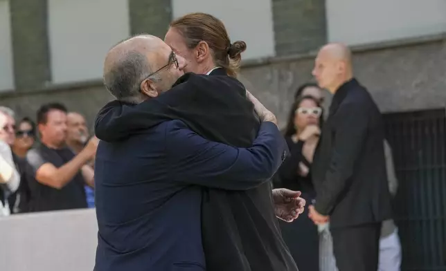 Italian film director Giuseppe Tornatore, left, is hugged as he arrives to pay his respects to fashion designer Giorgio Armani, lying in state at the Armani/Teatro in Milan, northern Italy, Saturday, Sept. 6, 2025. (AP Photo/Antonio Calanni)