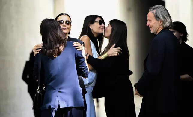 Mourners for fashion designer Giorgio Armani, who is lying in state at the Armani/Teatro in Milan, northern Italy, exchange condolences, Saturday, Sept. 6, 2025. (AP Photo/Nicola Marfisi)