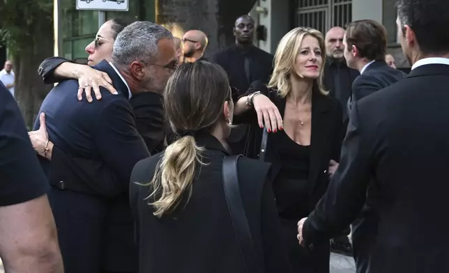 Staff of Giorgio Armani Spa gather outside the Armani/Teatro in Milan, northern Italy, after the hearse with the casket of designer Giorgio Armani, who died Thursday at age 91, left, Sunday, Sept. 7, 2025. (AP Photo/Nicola Marfisi)